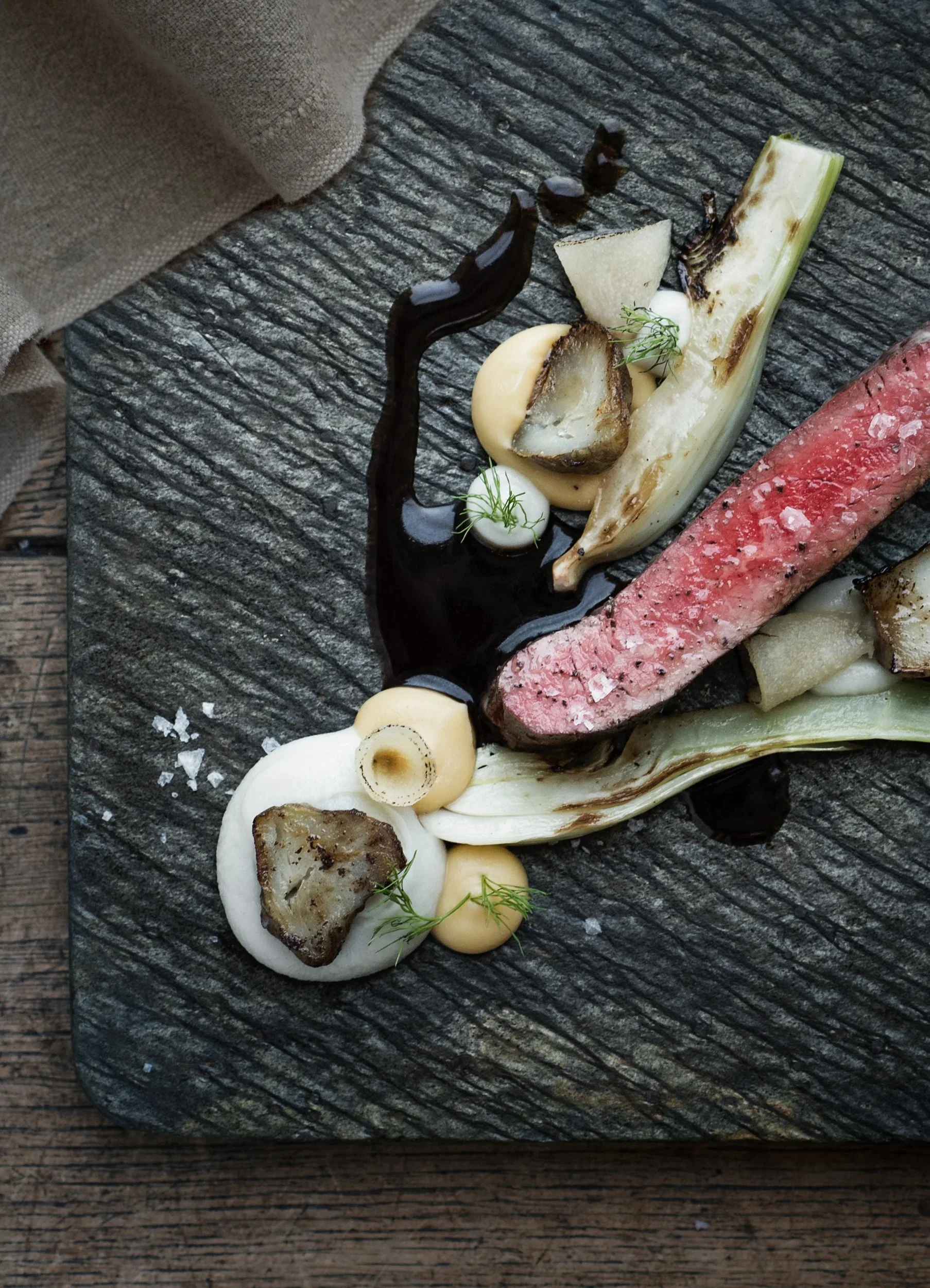 Detailed overhead shot of a gourmet steak dish on a slate plate.